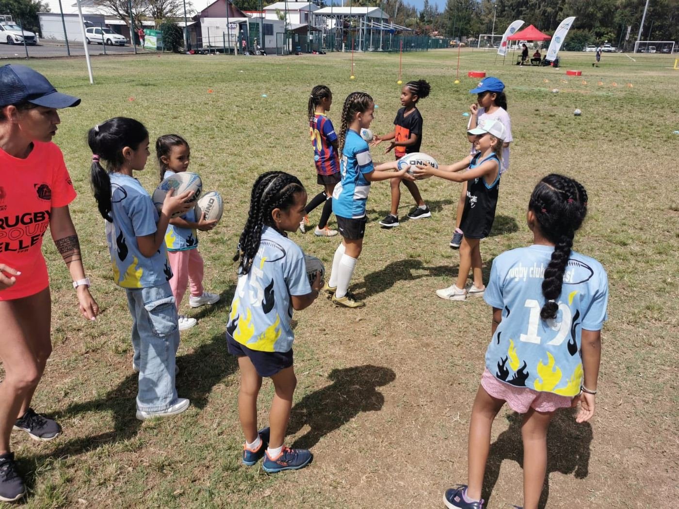 Séance de rugby scolaire : des enfants s'échangent le ballon avec une éducatrice